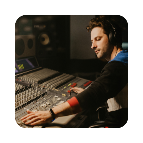 Man sitting at audio mixing board in a music studio.