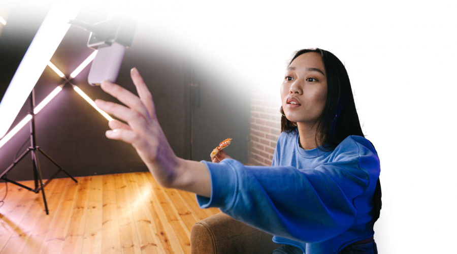 Woman filming a TikTok in front of a ring light and iPhone.